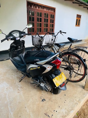 A scooter parked in front of a building with a window and a door.
