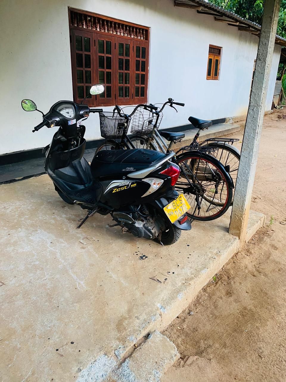 A scooter parked in front of a building with a window and a door.