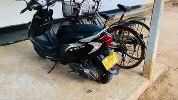 A scooter parked in front of a building with a window and a door.