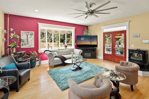 Una sala de estar con chimenea, televisor y un ventanal grande.