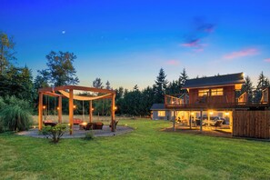 A two-story wooden house with a covered outdoor seating area and a swing set. - Grayson B&B — Sun-Drenched Executive Suite — Woodinville Wine Country (Monroe)