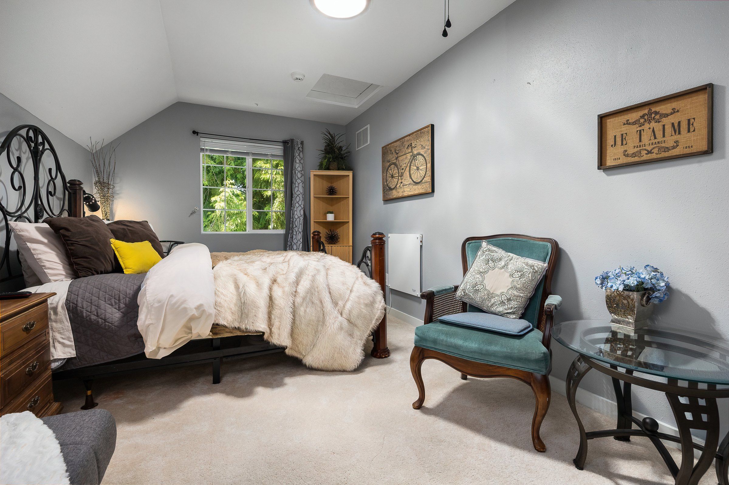 A bedroom with a bed, a chair, a table, and a window.