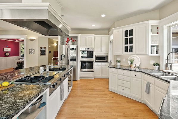 A modern kitchen with white cabinetry, stainless steel appliances, and a granite countertop.
