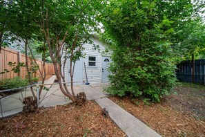 A residential backyard with a wooden fence, a garage, and a tree. - Cozy basement nook in the heart of Edmonton. (Edmonton)
