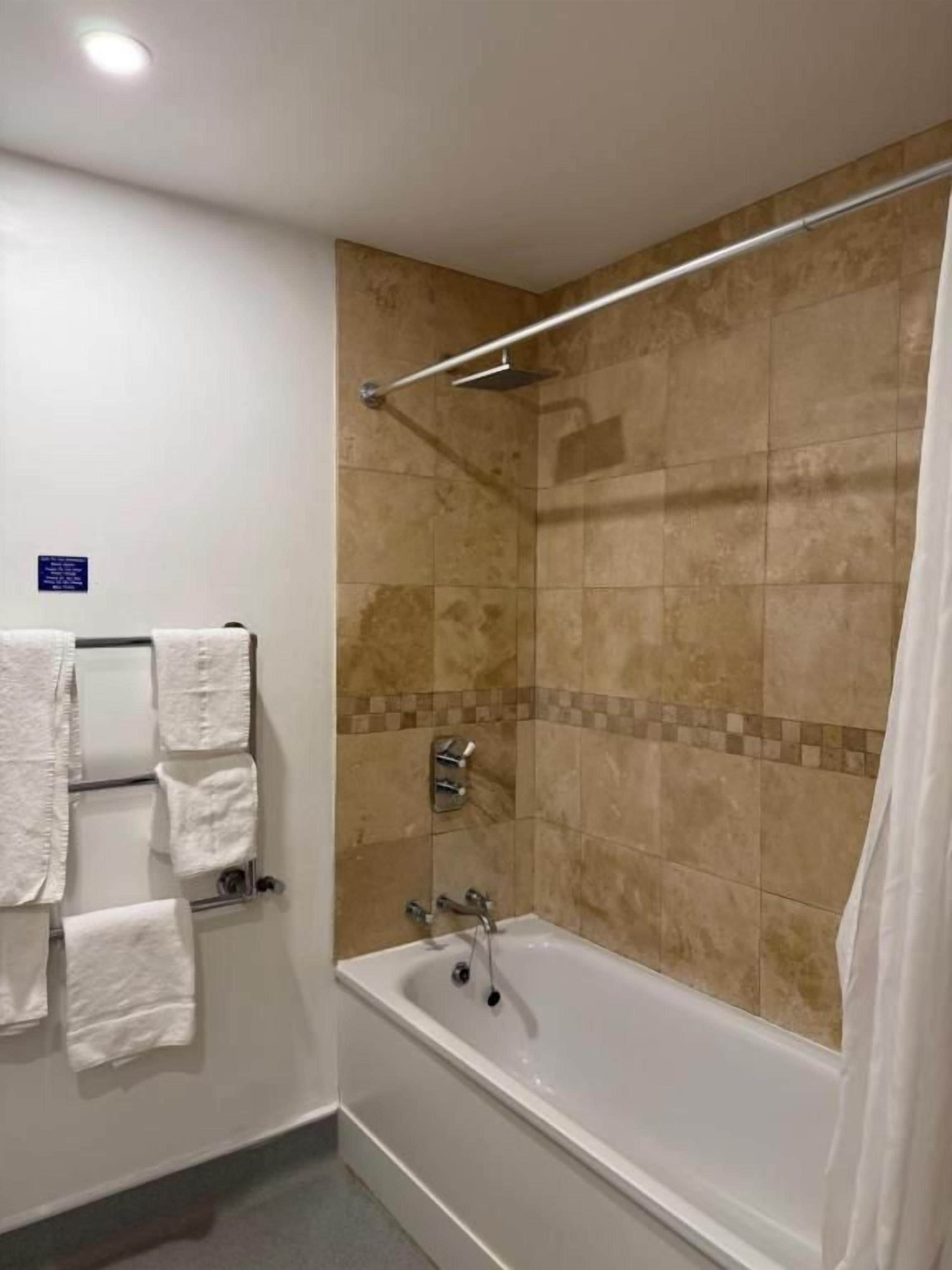 A bathroom with a bathtub, a towel rack, and a shower curtain.
