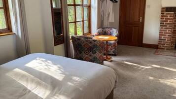 A bedroom with a bed, a chair, a small table, and a fireplace.