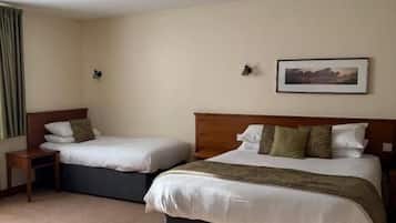 A hotel room with two beds, a nightstand, a framed picture on the wall, and a carpeted floor.
