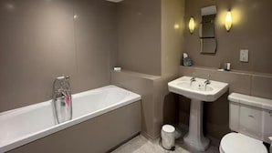 Un baño moderno con bañera, lavamanos e inodoro.