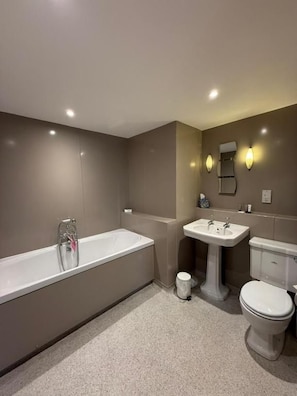 Un baño moderno con bañera, lavamanos e inodoro.
