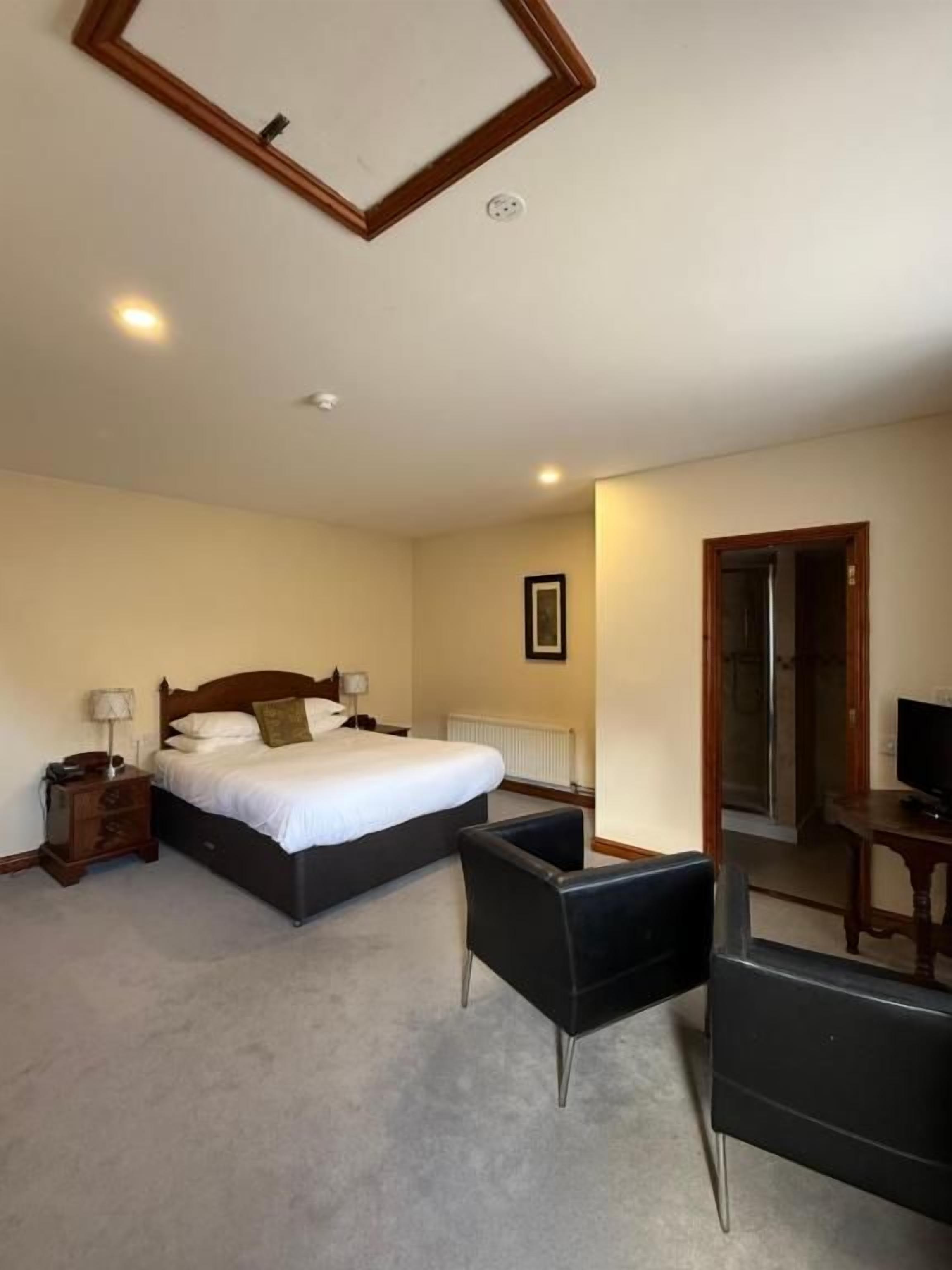 Una habitación de hotel con cama, escritorio, silla y televisor.