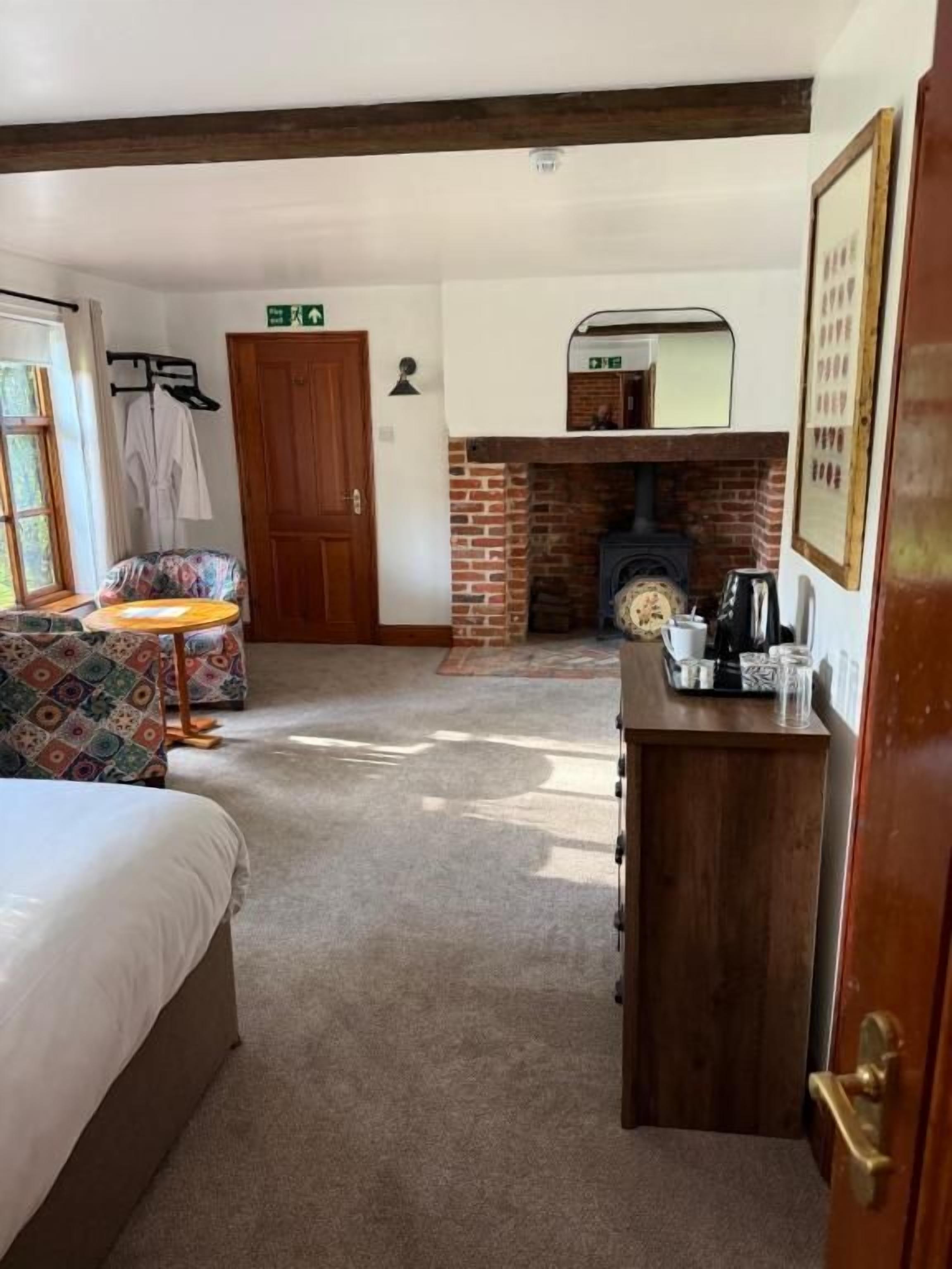 Una habitación con cama, una mesita, chimenea y una puerta.