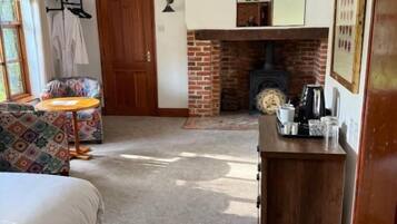 Una habitación con cama, una mesita, chimenea y una puerta.