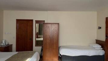 Habitación de hotel con dos camas, un armario, un escritorio y un cubo de basura.