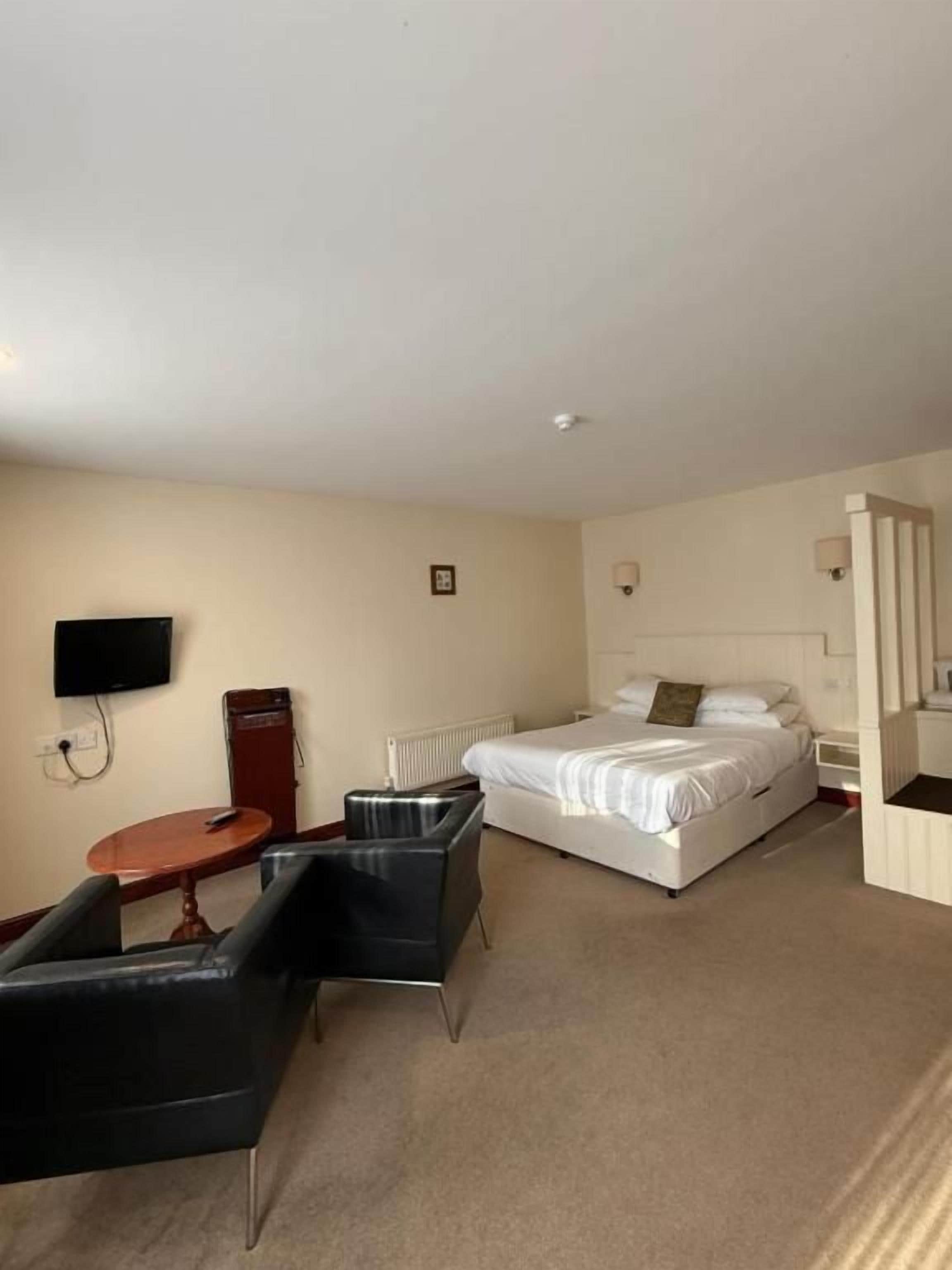 A hotel room with a bed, a TV, a desk, and a chair.