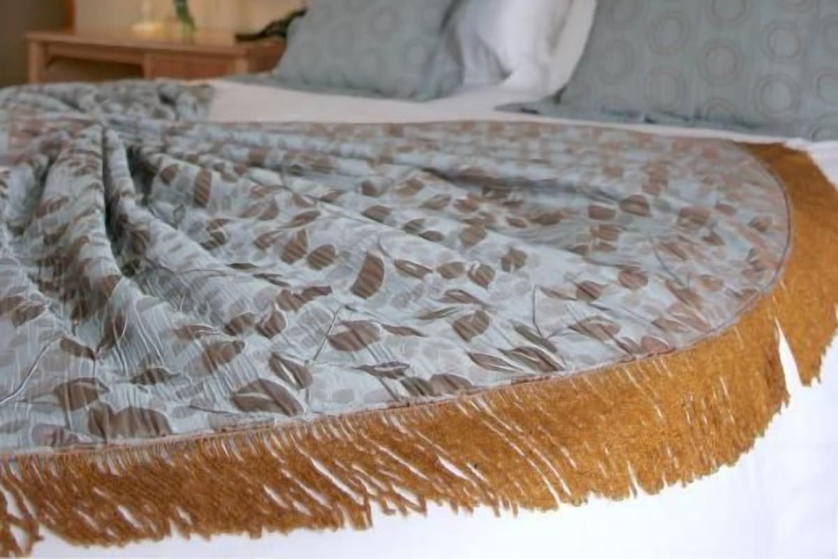 Una cama con dosel, una mesita de noche con lámpara y un adorno en la pared.