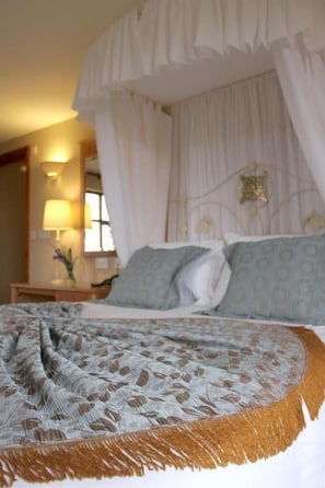 A bed with a canopy, a bedside table with a lamp, and a wall-mounted decoration.