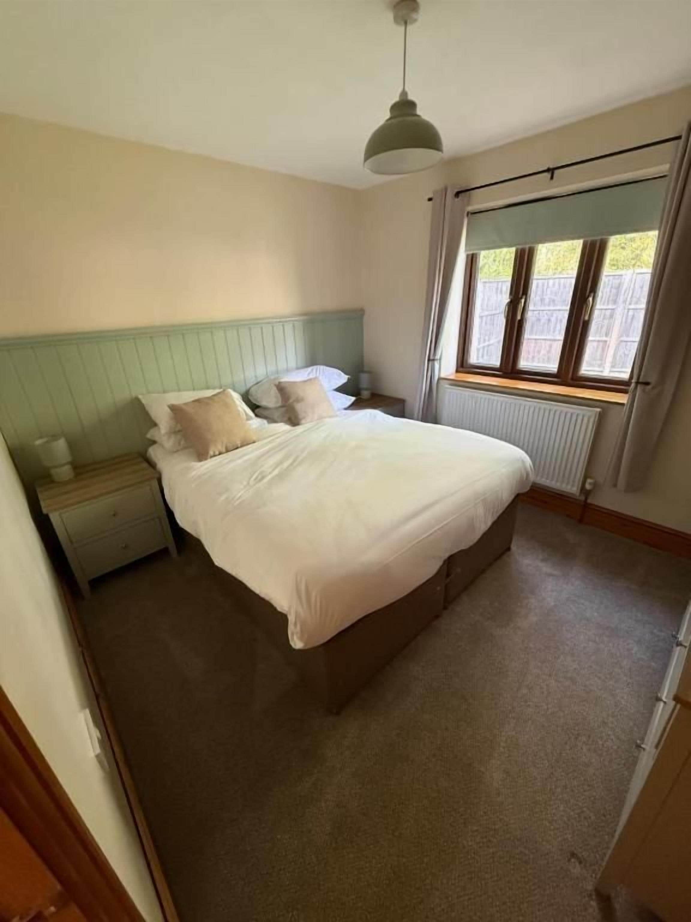 Ein Schlafzimmer mit Bett, Nachttisch und Fenster mit Vorhängen.