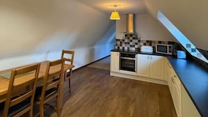 Una cocina pequeña y moderna con una mesa de comedor y sillas, un microondas y un salpicadero a cuadros.