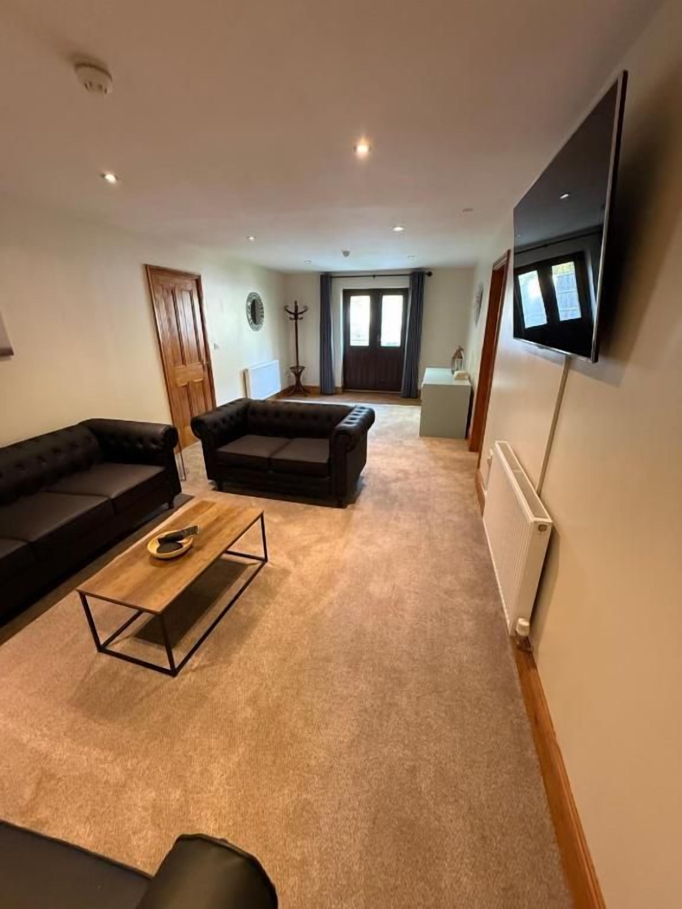 A living room with a sofa, a coffee table, a TV mounted on the wall, and a radiator.