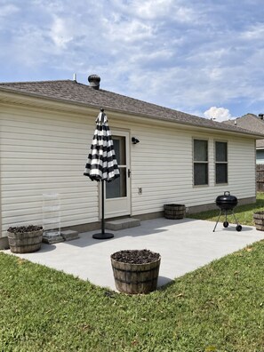 A residential house with a covered patio, a grill, and a striped umbrella. - Wonderful 3-bedroom house with AC in peaceful Morrilton (Morrilton)