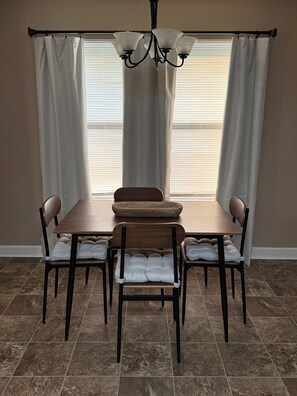 A dining area with a table and four chairs, a chandelier, and a window with blinds. - Wonderful 3-bedroom house with AC in peaceful Morrilton (Morrilton)