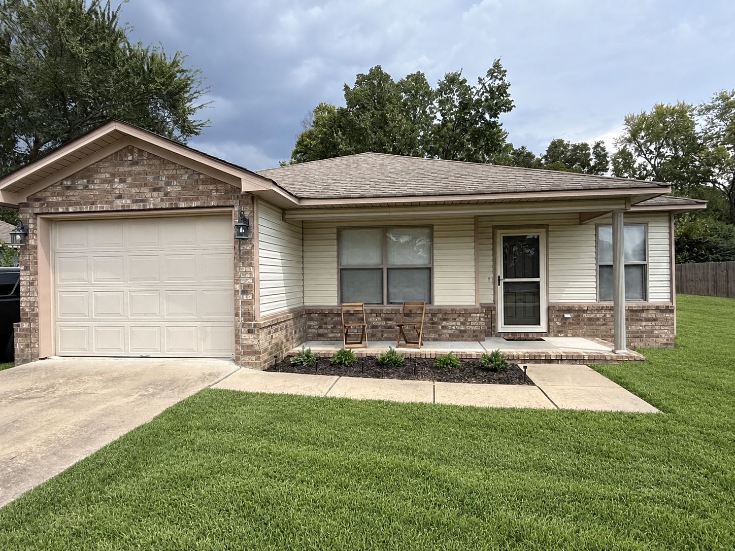 A two-story house with a garage, a front porch, and a well-maintained lawn.