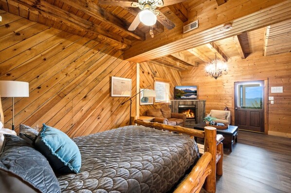A cozy room with a bed, a fireplace, and a television.