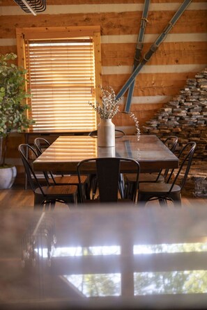 A wooden dining table with chairs, a vase with dried flowers, and a window with blinds. - Endless Views - Game Room, Arcade, Hot Tub! (Sevierville)