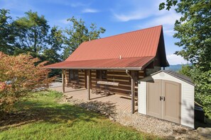 A log cabin with a covered patio, a small shed, and a view of the surrounding landscape. - Endless Views - Game Room, Arcade, Hot Tub! (Sevierville)