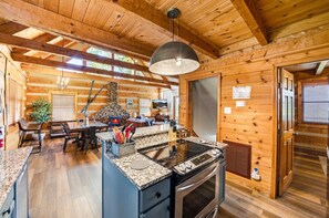 A cozy cabin interior with a kitchen area featuring a granite countertop, a built-in stove, and a stone fireplace.