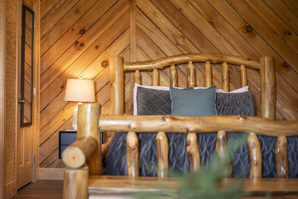 A wooden bed with a headboard, a bedside lamp, and two pillows.