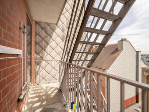 Ein Balkon mit Metallgeländer, einer Kachelwand und Blick auf die Stadtlandschaft.