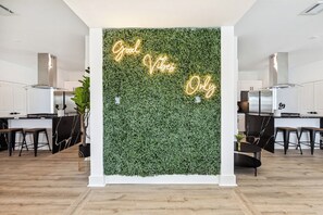 Cozinha moderna com parede verde e um letreiro de neon com a frase 'Good Vibes Only'.