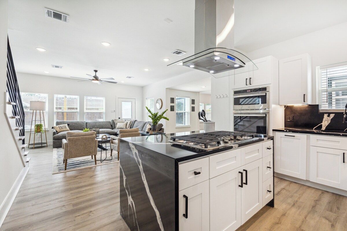 A spacious kitchen with white cabinets, a central island, and a built-in oven.