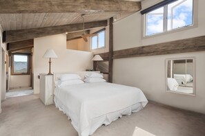 A bedroom with a large bed, two bedside lamps, a mirror, and a window with a view. - Snowmass Retreat: Vaulted Ceilings, Wood FP, Balcony W/ Grill & Great Views, W/D, Parking, Pool & HT (Snowmass Village)