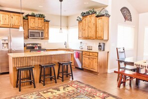 A kitchen with wooden cabinets, a stainless steel refrigerator, a microwave, a kettle, and a coffee maker.