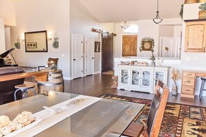 A spacious living area with a piano, a dining table, and a kitchen area with cabinets and a refrigerator. - Ranch Lodge for 24 Guests (Grantsville)