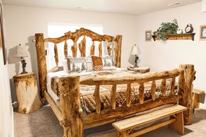 A rustic wooden bed with a bench, two bedside tables, and a wall-mounted shelf with decorative items.