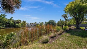 A residential area with a lake, a house, and a tree. - Seaturtle Cottage by Avantstay Lakefront + Firepit + Grill Vanderbilt Beach (Naples)