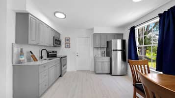 A modern kitchen with grey cabinets, stainless steel appliances, and a wooden dining table.