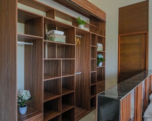 A wooden storage unit with multiple shelves and compartments, a marble countertop, and a potted plant.