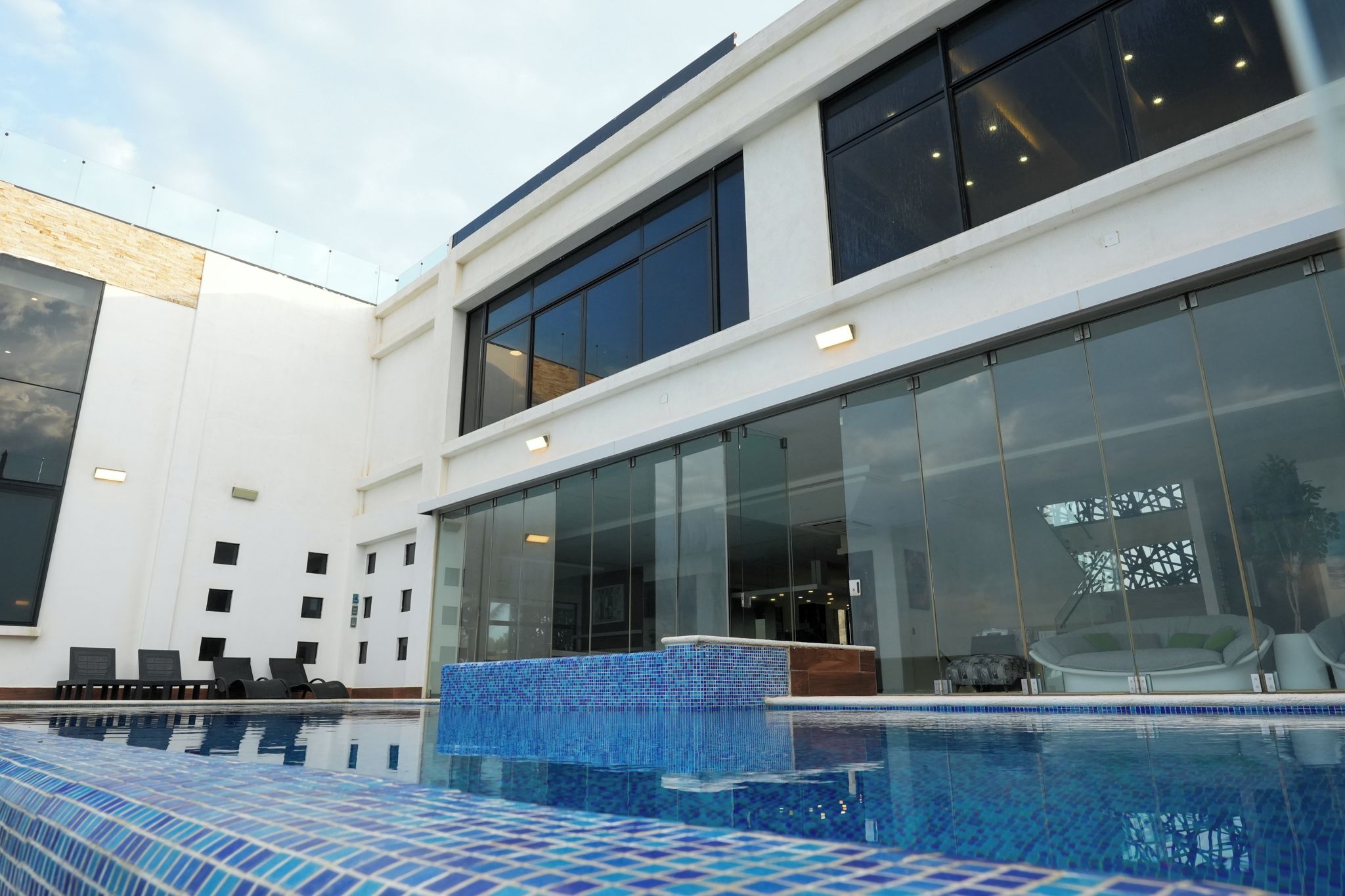 Un bâtiment moderne doté d’une piscine, de grandes fenêtres et d’une façade en verre.