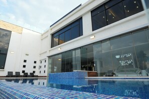 A modern building with a swimming pool, large windows, and a glass facade.
