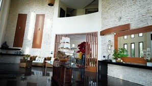 A spacious lobby with a high ceiling, a large ship model, and a wooden reception desk. - Aurea Vita (Tres Vidas Acapulco Diamante)