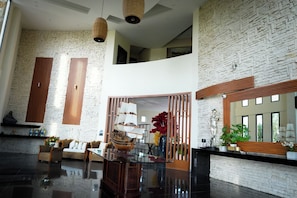 A spacious lobby with a high ceiling, a large ship model, and a wooden reception desk. - Aurea Vita (Tres Vidas Acapulco Diamante)
