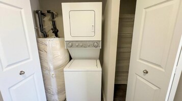 Un lavadero compacto con lavadora y secadora, calentador de agua y armario de almacenamiento.