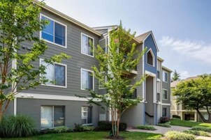 A multi-story residential building with a flat roof, large windows, and a well-maintained lawn.