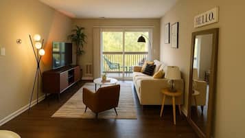 A living room with a sofa, armchair, TV, and a 'HELLO' sign on the wall.