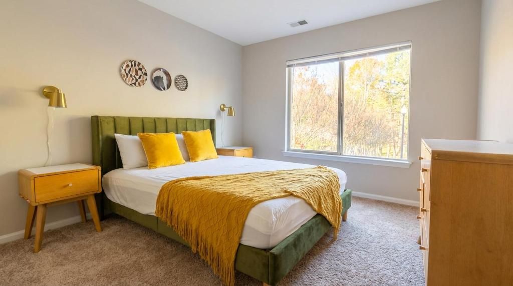 Un dormitorio con cama, mesitas de noche, cómoda y ventana con luz natural.