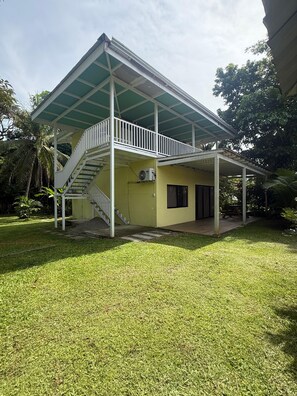 A two-story house with a covered patio, a staircase, and an air conditioning unit. - Casa Melda | Walk to the Beach & GandocaManzanillo (Manzanillo)